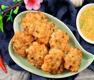 Đĩa chả mực tôm giã tay chiên vàng ươm, nóng hổi được bày đẹp mắt trên đĩa sứ màu xanh ngọc hình trái tim, bên cạnh là bát nước chấm chua ngọt tỏi ớt hấp dẫn. Sản phẩm hải sản cao cấp của Hải Sản Hoàng Ngư.